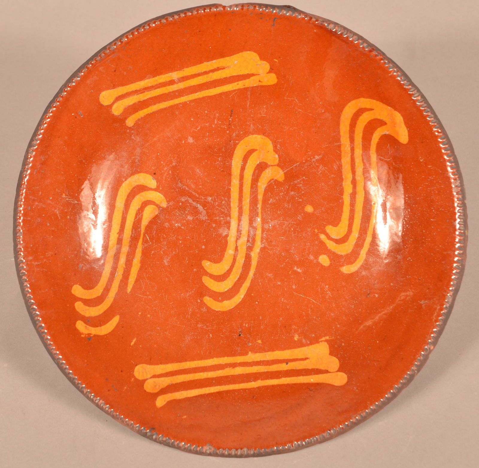 Pennsylvania 19th Century Redware Charger.: Pennsylvania 19th Century Redware Charger. Yellow slip decoration with coggle wheel edge. 12-1/2" diam. Condition: Good with edge chips and surface wear.