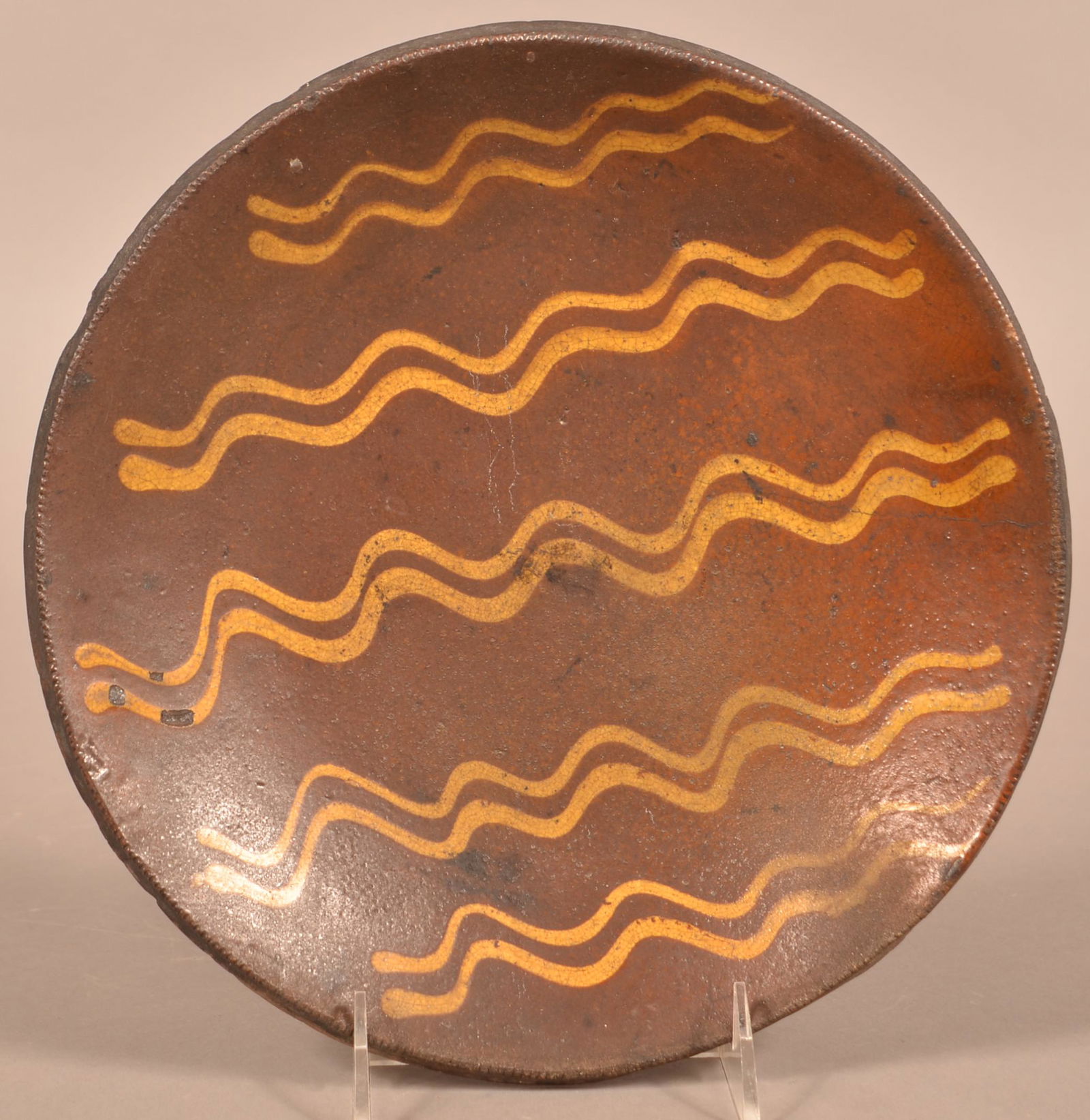 Pennsylvania 19th Century Redware Plate.: Pennsylvania 19th Century Redware Plate. Yellow slip decoration with coggle wheel edge. 10-1/4" diam. Condition: Good with rim chips.