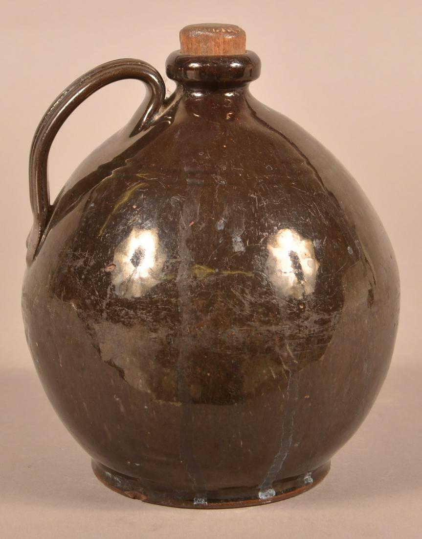 PA 19th Century Manganese Glazed Redware Jug.: Pennsylvania 19th Century Manganese Glazed Redware Jug. Rounded rim, ovoid body and applied ribbed strap handle. 7-1/2"h. Condition: Good with wear.