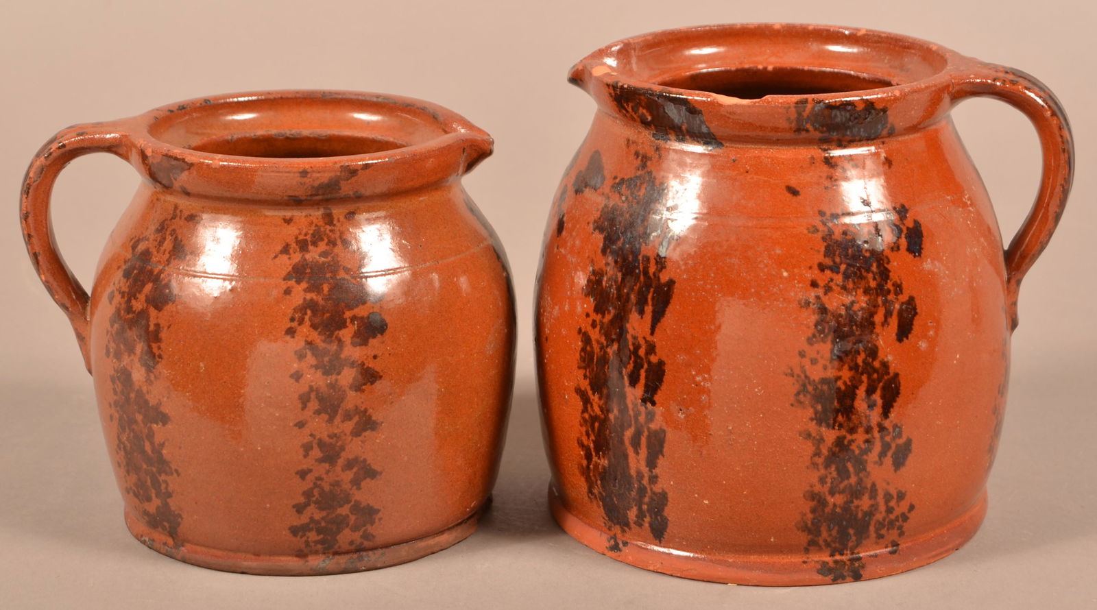 2 Redware Pitchers with Manganese Sponge Decoration.: Two Antique Redware Pitchers with Manganese Sponge Decoration. 6" and 7"h. Condition: Good with rim chips. No lids.
