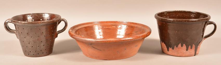 Three Pieces of Antique Glazed Redware.: Three Pieces of Antique Glazed Redware. Large bowl with molded edge, 15" diam., colander with strap handles, 6-3/4"h. and a tapered bowl with strap handle, 6-3/4"h. Condition: Good with chips and line