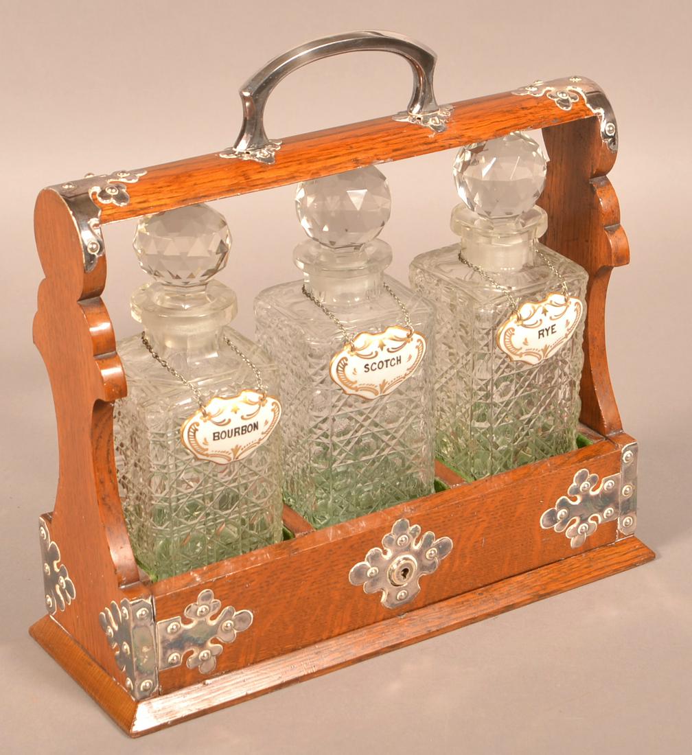 English Ship Captain's Three Bottle Tantalus Set.: Antique/Vintage English Ship Captain's Three Bottle Tantalus Set. Cut crystal cane pattern decanters in an oak silver mounted locking case. 14"h. x 14"w. Condition: Good with minor wear.