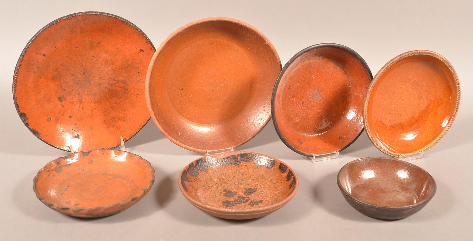 Seven Antique Glazed Redware Plates.: Seven Antique Glazed Redware Plates. Largest 10-1/2" diam. Condition: Good with chips and lines.