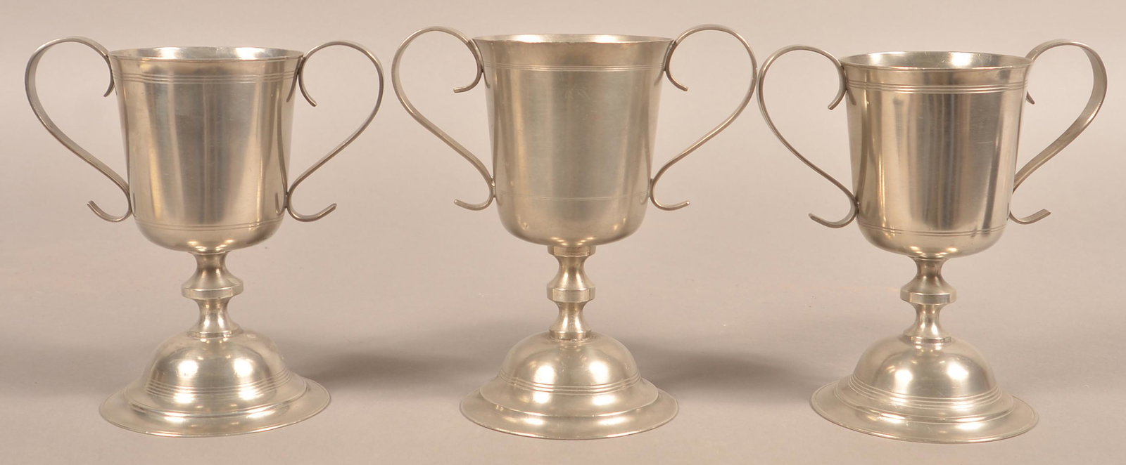 Three Rare American Pewter Double Handled Chalices.: Three Rare American Pewter Double Handled Chalices. One signed and two attributed to Israel Trask, Beverly, Mass., 1807–1856. 7" and 7-1/4"h. Condition: Very good with minor wear.