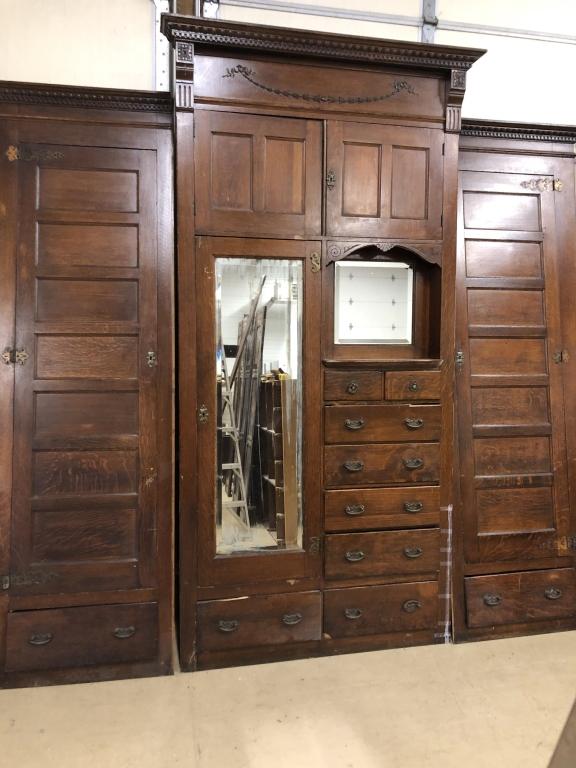 Chestnut Built-in Wardrobe Facade: w/ central piece having 2- two paneled overhead doors over mirrored wardrobe door & 8 drawers flanked by two- 7 paneled doors with lower drawer with ornate carved cornice. 123" W x 108"H. Condition: G