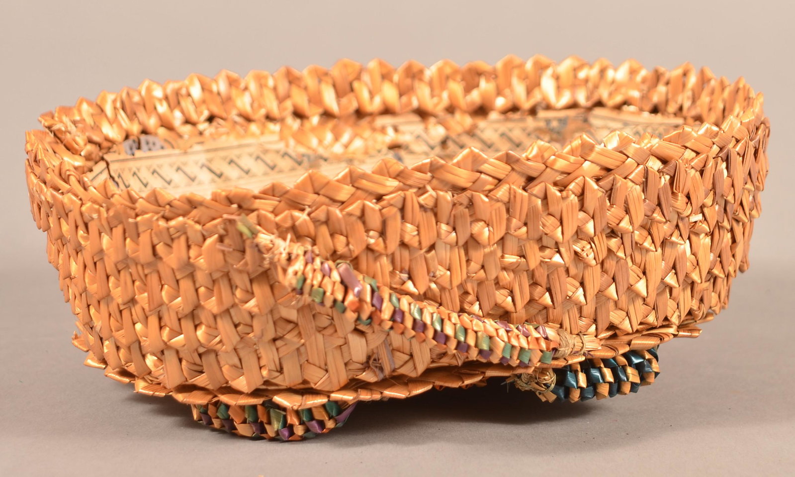 Pennsylvania Folk Art Oval Corn Husk Sewing Basket.: Pennsylvania Folk Art Oval Corn Husk Sewing Basket. With colorful died elements and wallpaper lining. 3"h. x 7"w. x 6"d. Condition: Very good with minor loss.