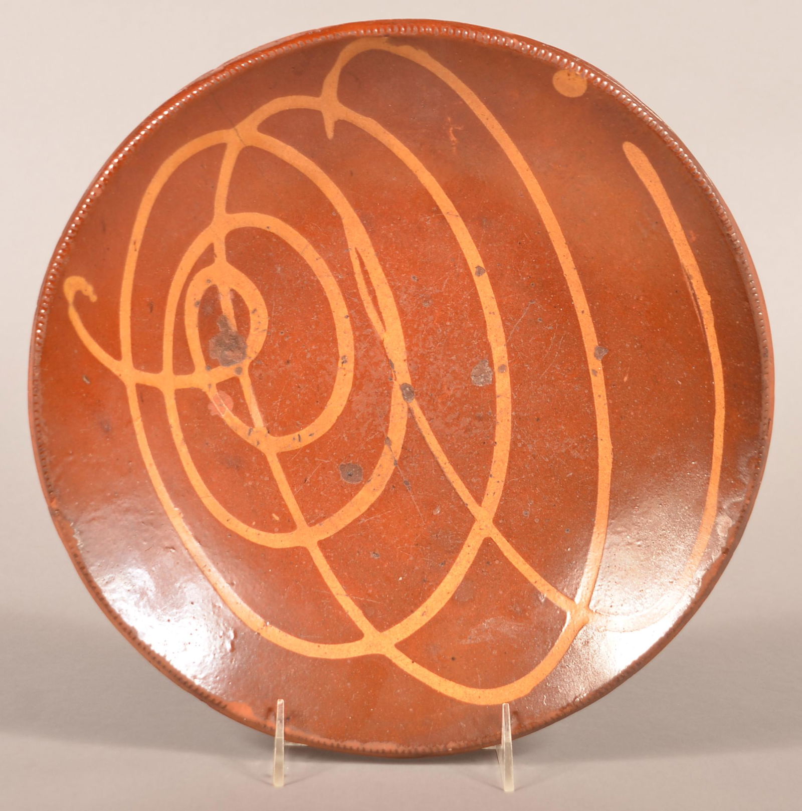 Yellow Slip-Decorated Redware Pottery Charger.: 19th Century Yellow Slip-Decorated Redware Pottery Charger. Coggle wheel edge. 12" diam. Condition: Good with edge chips and surface wear.