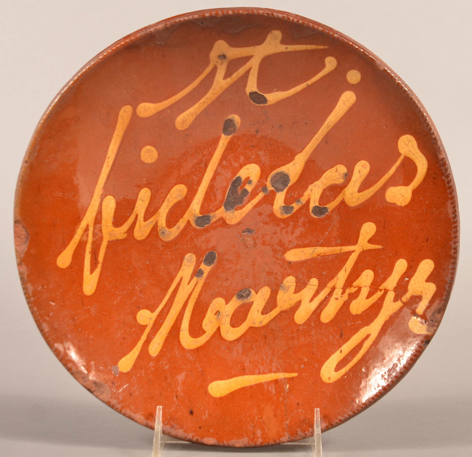 Yellow Slip-Decorated Redware Plate "St. Fidelas: Yellow Slip-Decorated Redware Plate Inscribed "St. Fidelas Martyr,". Norwalk, CT origin, mid 19th century, with coggle wheel edge. Condition: Flakes to interior, rim chips. 4-3/4" crack from rim and a