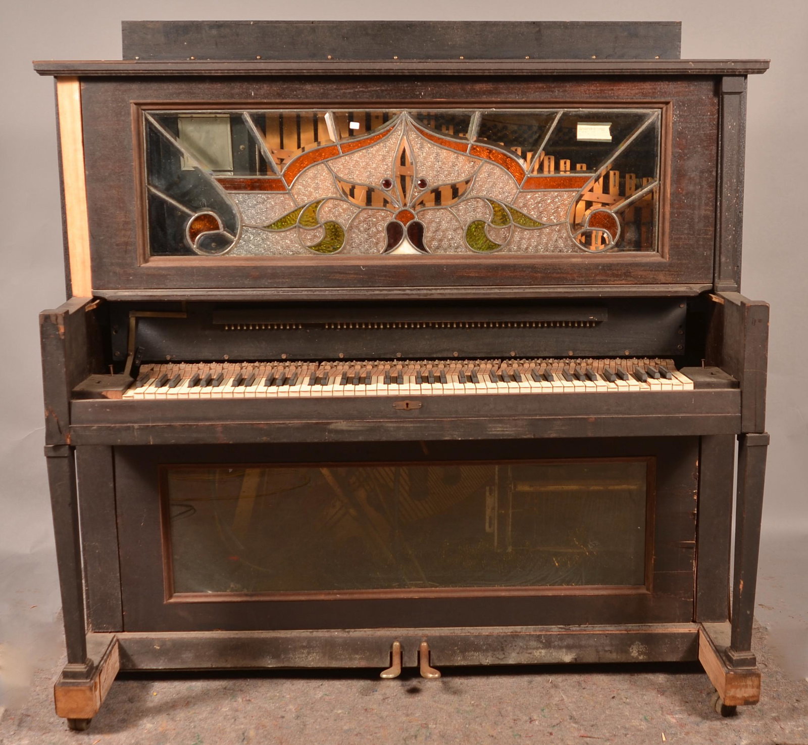 Seeburg Mahogany Upright Player Piano.: Seeburg Mahogany Upright Player Piano. With stool. Leaded glass floral and foliate tablet. 61-1/2"h. x 64"w. x 31"d. Condition: Needs restoration. Missing pump.