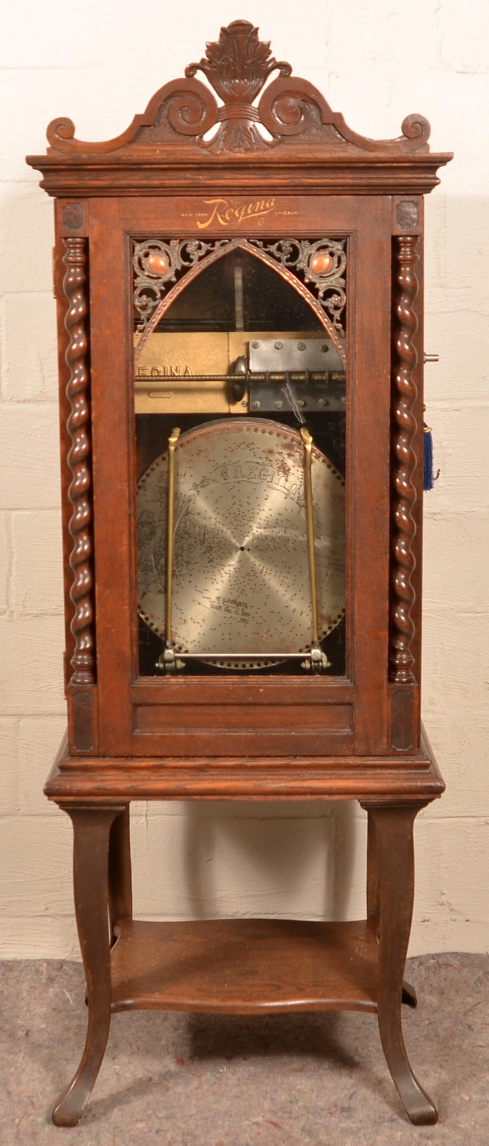 Regina Quarter Sawn Oak Case Upright Disc Player.: Regina Quarter Sawn Oak Case Upright Coin Op Auto-Change Disc Player. Applied shell and scroll cornice, glass door with brass ormolu mountings, flanked by spiral turned columns, molded and skirt, lowe