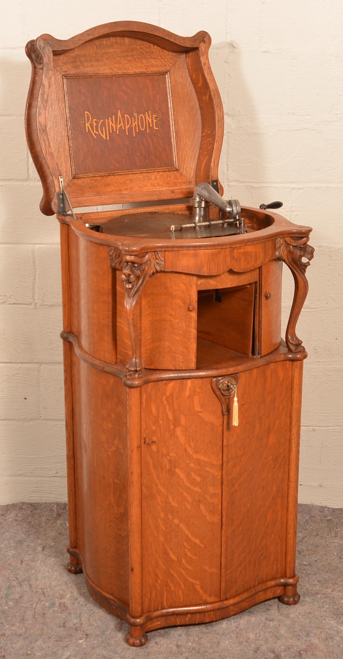 Reginaphone Oak Case Disc/Record Combination Player.: "Reginaphone Quarter Sawn Oak Case Disc/Record Combination Player. SN 2400409. Lion carved case. Accompanied with 31 15-1/2" discs and record adapter. 49-1/2"h. x 22"w. x 20"d. Condition: Very good wi