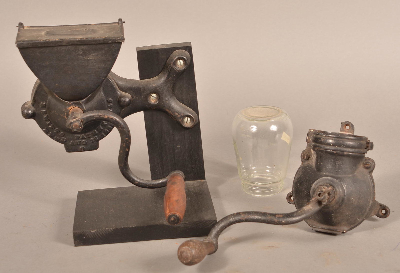 Two Antique Cast Metal Wall-Mount Coffee Mills.: Two Antique Cast Metal Wall-Mount Coffee Mills. Jars not original. Tallest 9-1/2"h. Condition: Good with use wear.