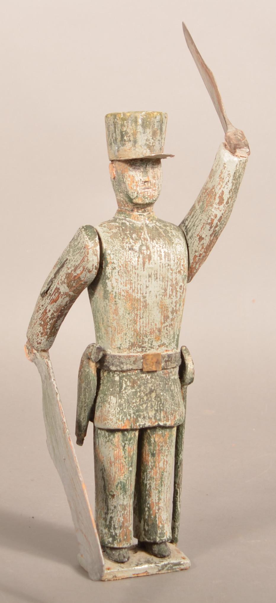 Antique Folk Art Wood U.S. Civil War Soldier Whirligig.: Antique Folk Art Wood U.S. Civil War Soldier Whirligig. Remnants of green paint. Uniformed soldier with shako cap having a pistol and sword on belt. 17-1/4"h. to top of arm paddle. Condition: Good wit