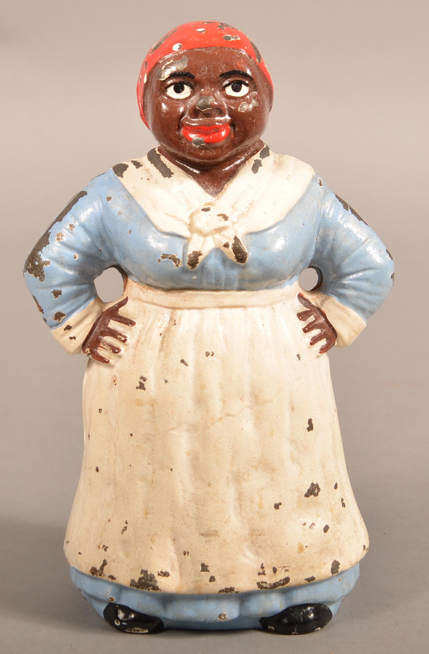 Hubley Cast Iron Mammy With Hands On Hips Doorstop.: Hubley Cast Iron Mammy With Hands On Hips Doorstop. Depicts full-figure mammy wearing traditional apron and scarf. Blue dress paint variation. 8-3/4"h. Condition: Condition: Good with wear.