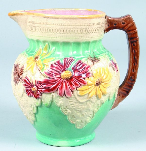 Majolica tin-glazed earthenware Floral and Lace em: Majolica tin-glazed earthenware Floral and Lace embossed water pitcher, on turquoise ground with pink interior. Condition: Chip on spout.