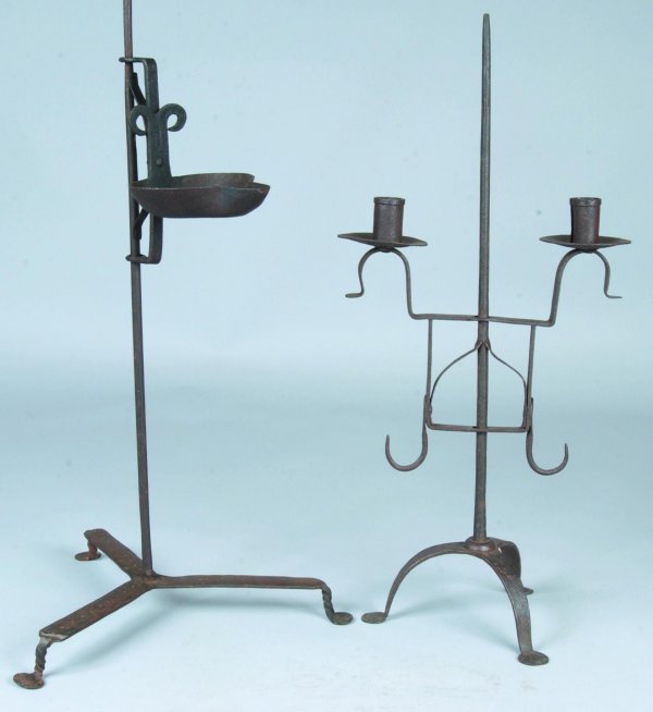 Two Wrought Iron Lighting Devices, first is an Adj: Two Wrought Iron Lighting Devices, first is an Adjustable Grease lamp with shaped bowl, twisted and flatten feet, and second is an Adjustable double socket candle stand with arched legs and flatten fe