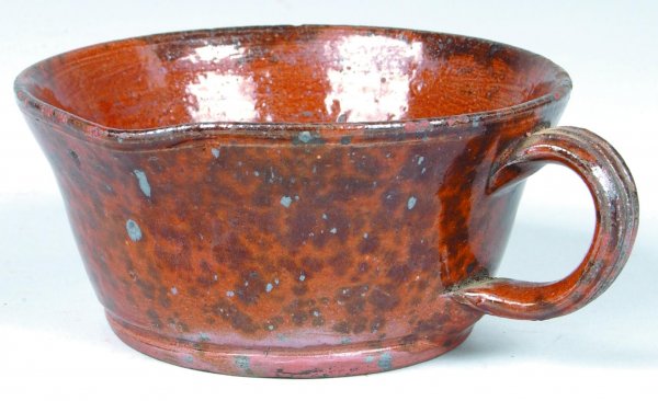 Redware Porringer, round form with pouring spout a: Redware Porringer, round form with pouring spout and loop handle, manganese speckle decoration, 2-3/4" h., (good condition with minor edge nips).
