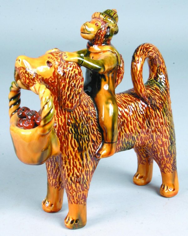Large Breininger Redware Standing Dog with Monkey R: Large Breininger Redware Standing Dog with Monkey Rider Figure, (Copy of Bell Pottery) dog with basket of fruit in mouth, mottled glaze, signed LB 1993,9"h.x8 ¼"l.x3 ¼"w. (very good condition).