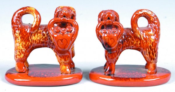 Pair of Breininger Miniature Redware Dog Figures, (: Pair of Breininger Miniature Redware Dog Figures, (Copies of Bell Pottery) standing dogs with head turned and basket of fruit in mouth, on oval bases, mottled glaze, both signed Breininger Pottery 199