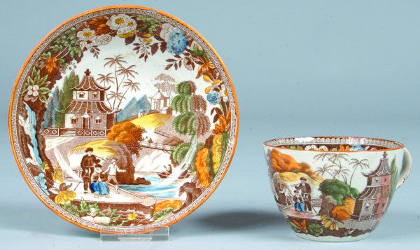Salopian China Oriental Views Tea Cup and Saucer,: Salopian China Oriental Views Tea Cup and Saucer, polychrome transfer depicting pagoda, stream, boat and village, floral border, (cup with base nips and saucer with edge chip).