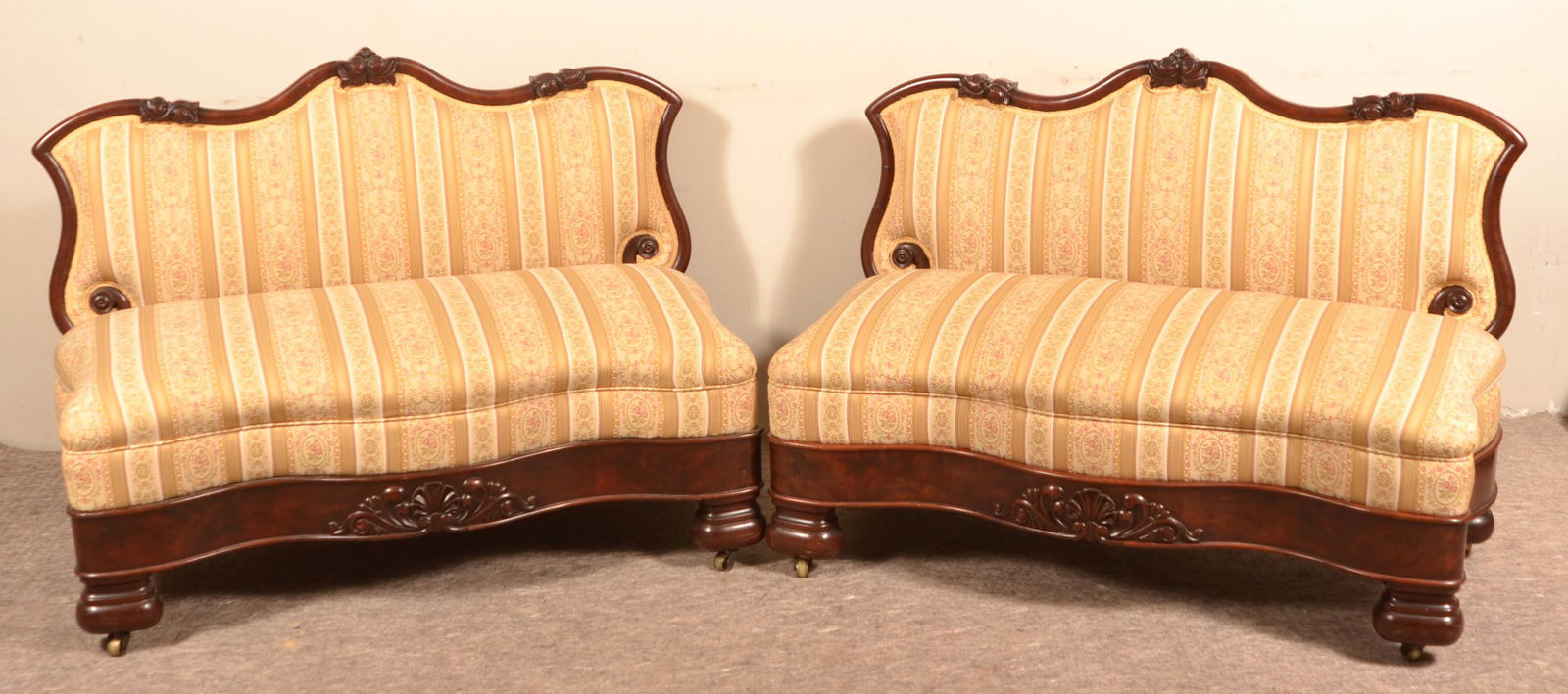 Pair of Empire Mahogany Upholstered Settees.: Pair of Empire Mahogany Upholstered Settees. Serpentine front and back with floral carved frames. Seat height 17"h, x 34"h. overall x 44"w. Condition Good with wear.