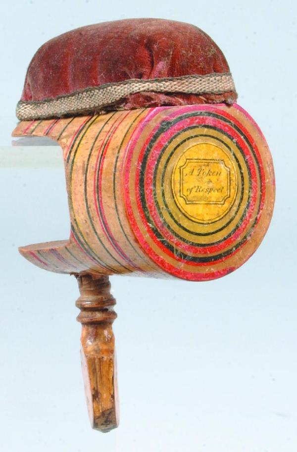 Wood Sewing Clamp having top Pin Cushion, decorate: Wood Sewing Clamp having top Pin Cushion, decorated with multi-colored striped and marked on end "A Token of Respect", 2 ½"l. Condition: Good.