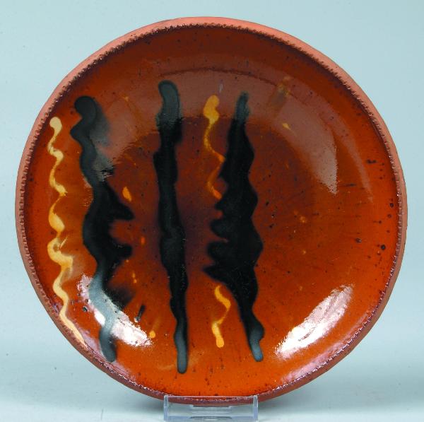 Redware Pottery Manganese and Yellow Slip Decorate: Redware Pottery Manganese and Yellow Slip Decorated Plate attributed to J. S. Henne, (Bernville, Pa.), with coggle-wheel edge and orange ground glaze. 8-1/4" diam. Condition: Good.