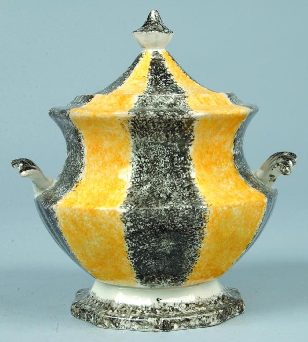 Bold Black and Yellow Rainbow Spatter Ironstone Ch: Bold Black and Yellow Rainbow Spatter Ironstone China Covered Bowl. Paneled form with scalloped finial and shell handles. 7-1/4" high. Condition: Handles repaired