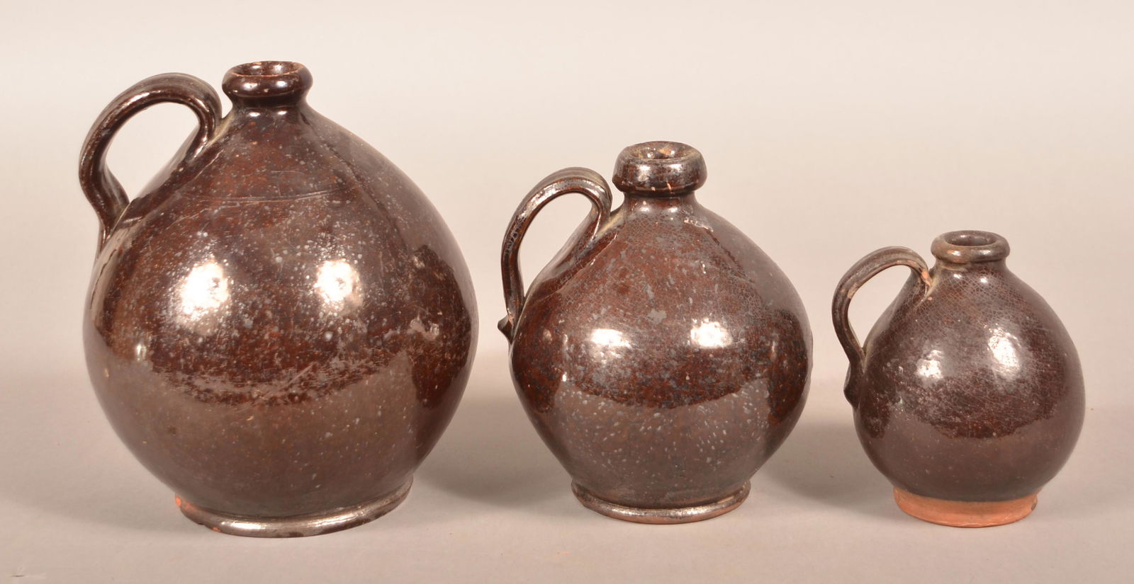 Three 19th Century Graduated-Glazed Redware Jugs.: Three 19th Century Graduated-Glazed Redware Jugs. Bulbous forms with applied ribbed loop handles. 5-1/4" to 8-1/4"h. Condition: Good with crazing and some chips.