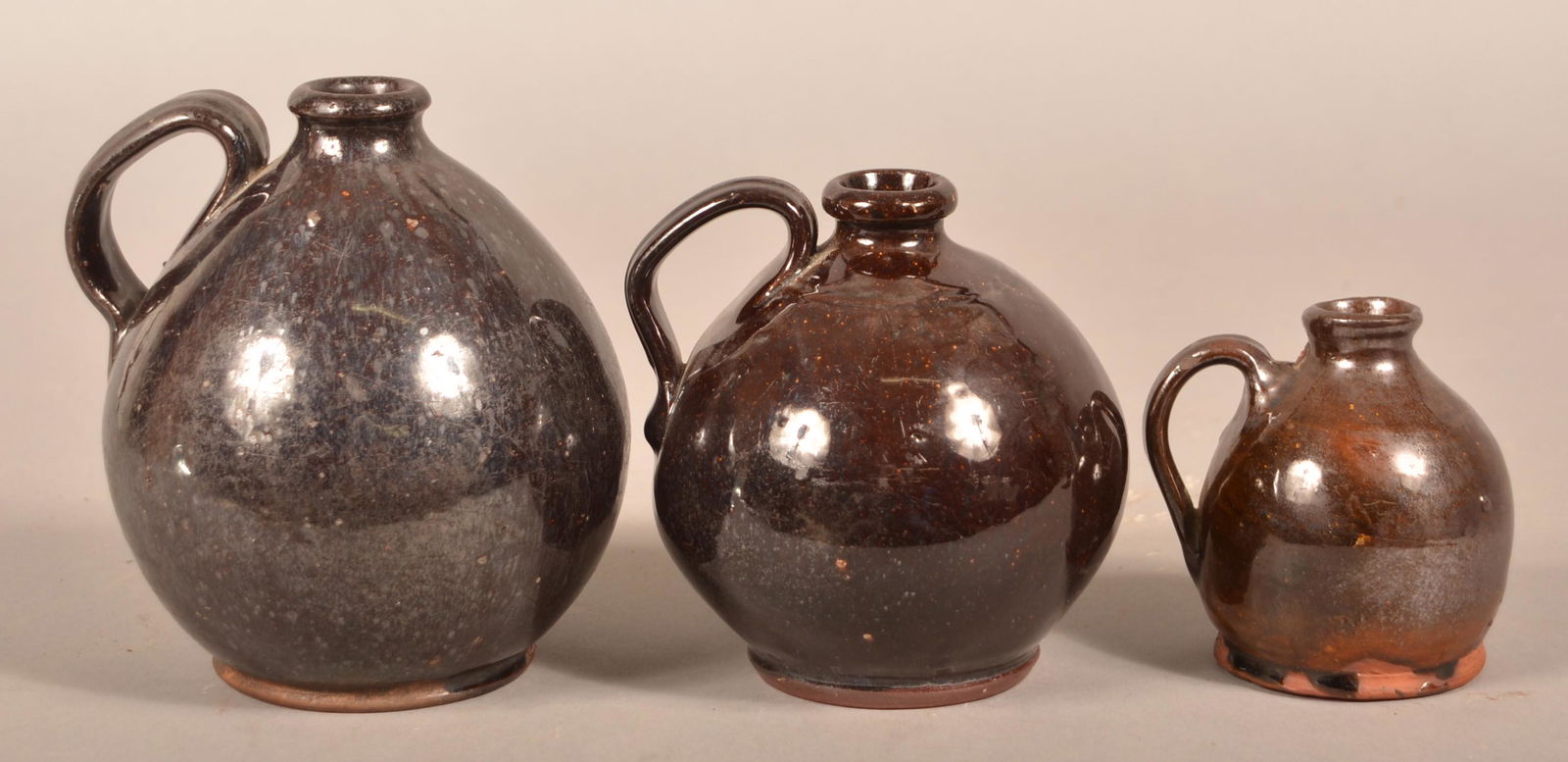 Three 19th Century Graduated Glazed Redware Jugs.: Three 19th Century Graduated Glazed Redware Jugs. Bulbous forms with applied loop handles. 4" to 6-1/4"h. Condition: Good with wear.