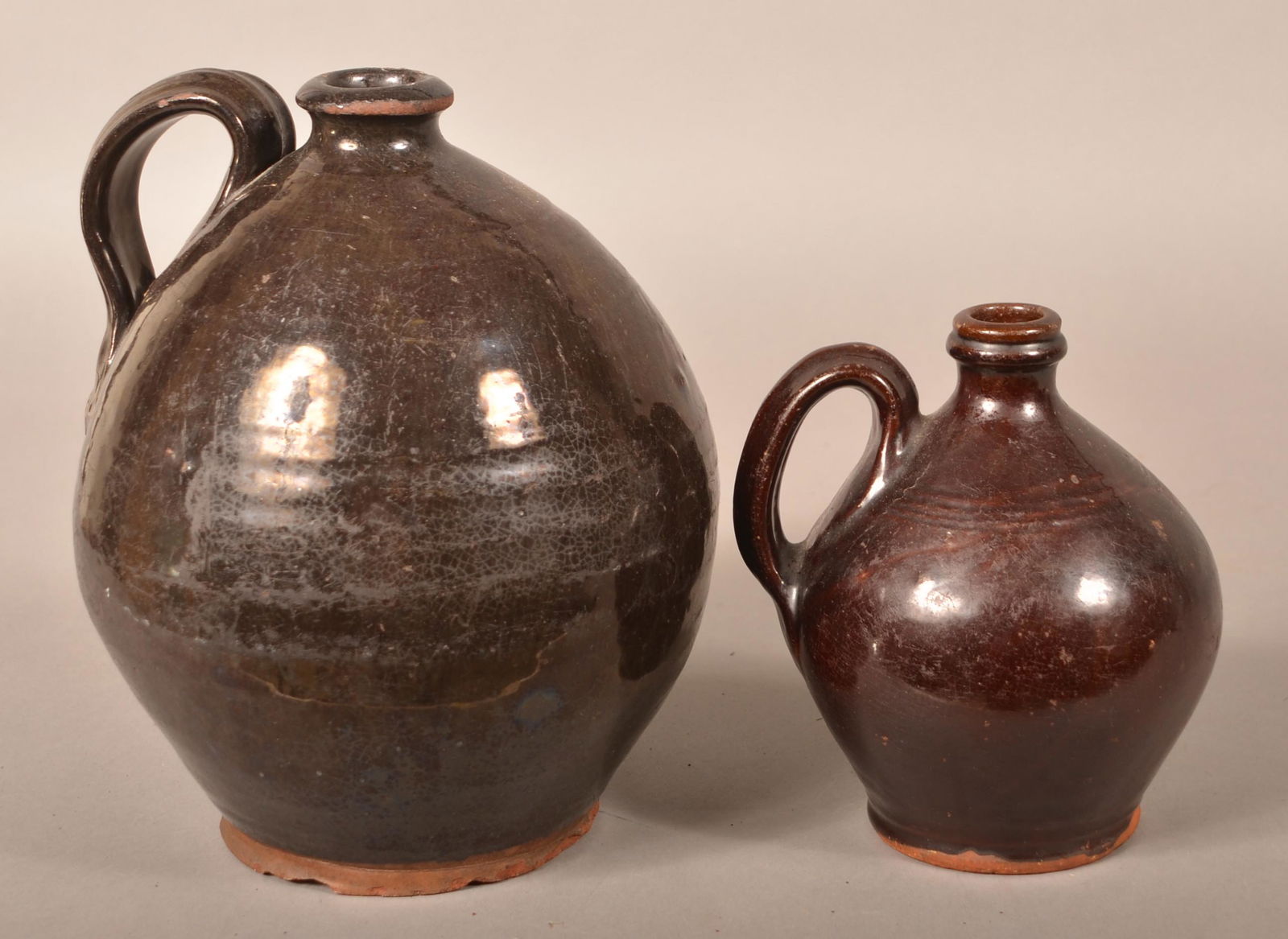 Two 19th Century Glazed Redware Jugs.: Two 19th Century Glazed Redware Jugs. Bulbous forms with applied ribbed loop handles. 7" and 10"h. Condition: Good with chips.