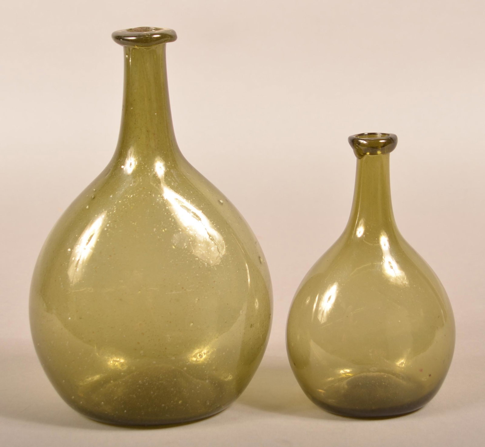 Two Blown Olive Green Glass Chestnut Bottles.: Two Blown Olive Green Glass Chestnut Bottles. Early 19th Century. Ovoid bodies, tapered cylindrical necks with applied mouth and concave bases with pontils. 6-1/2" and 9" high. Condition: Very good.