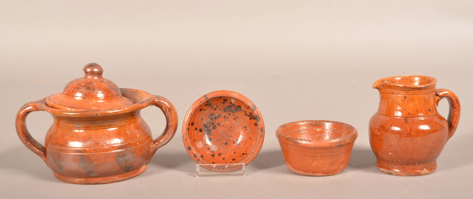 Four Pieces of 19th Century Glazed Redware.: Four Pieces of 19th Century Glazed Redware. Cream pitcher, covered sugar bowl, and two small bowls. Cream pitcher 4"h. Condition: Good with some chips and lines.