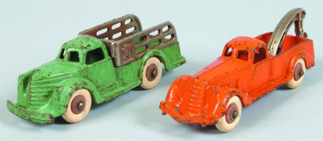 Two Hubley Cast iron Trucks white rubber balloon tir: Two Hubley Cast iron Trucks white rubber balloon tires; orange 2234-6 wrecker, 5 1/2" long and a green 2274-4 stake body truck, 5" long. Condition: Both good with minor chips on paint.