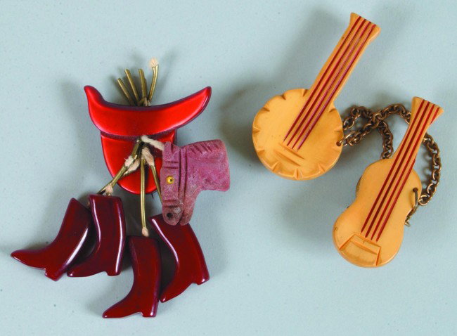 Two Bakelite Western Style Pins, saddle form with : Two Bakelite Western Style Pins, saddle form with boots, guitar and banjo, 3'h. and 2 1/2"h. Condition: Very good.