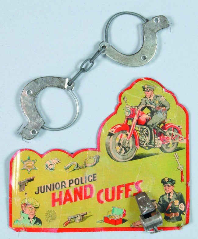 Junior Police Hand Cuffs, tin cuffs and whistle on: Junior Police Hand Cuffs, tin cuffs and whistle on lithograph illustrated backboard, (items loose), Made in Japan, 6-3/4" x 7-3/4", fair condition.