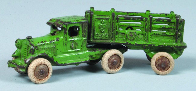 A. C. Williams Cast Iron W 88 Truck with Stake Bod: A. C. Williams Cast Iron W 88 Truck with Stake Body in original green paint and white rubber tires, 5 1/2" long. Condition: good with minor paint loss, original tires crazed.