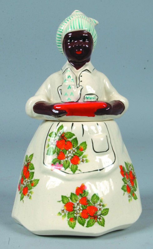 Black Memorabilia Cookie Jar, 11 1/4"h.; white cer: Black Memorabilia Cookie Jar, 11 1/4"h.; white ceramic Mammy type two part cookie jar,undre-glaze painted mold features and applied transfers of strawberries. Signed: McCoy on bottom. Condition: Good