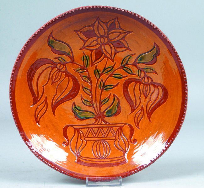 Foltz Pottery Decorated Redware Dish, 10" diam.; s: Foltz Pottery Decorated Redware Dish, 10" diam.; slip faced and incised decoration of three potted tulips, with coggle rim. Marked on bottom: "C. H. Foltz 1988". Condition: Good.