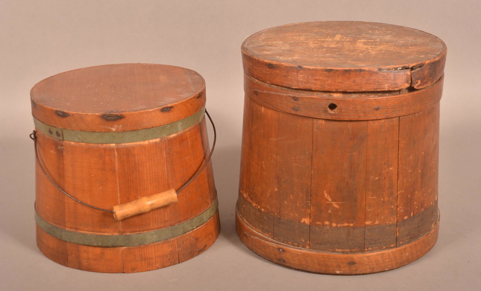 Two Antique Softwood Covered Firkins.: Two Antique Softwood Covered Firkins. 9" and 11-3/4"h. Condition: Fair to good. One missing handle and pegs.