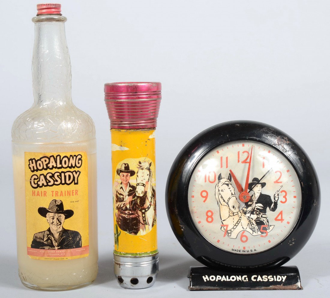 Three Pieces of Hopalong Cassidy Memorabilia. A gl: Three Pieces of Hopalong Cassidy Memorabilia. A glass bottle of Hair Trainer, Associated Brands Inc., c.1950, 9 1/2"h.; a lithograph decorated sheet metal flashlight and siren, mfg. by Ashe Flash, c.W