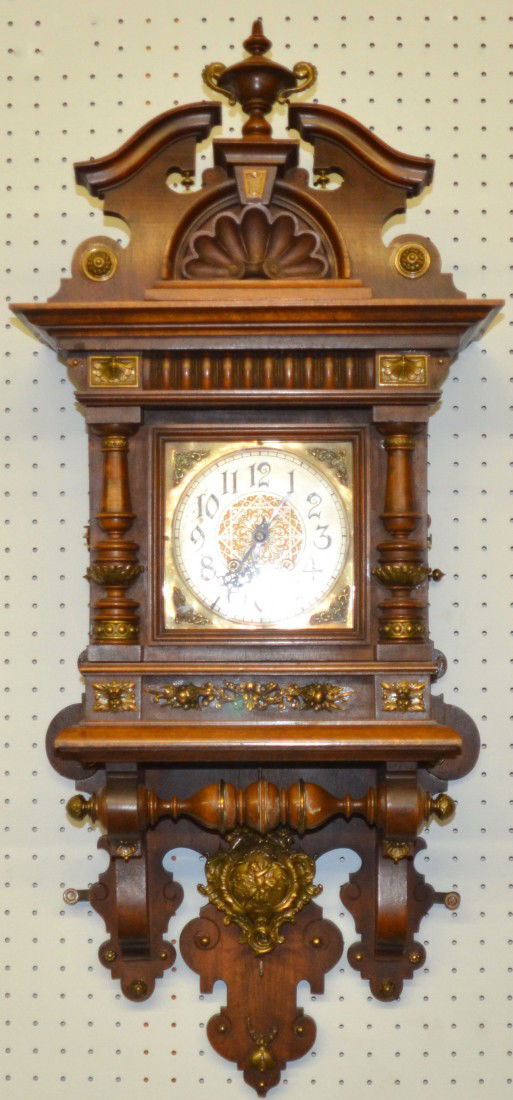 German Pendulum Wall Clock in Ornate Oak Case. Spr: German Pendulum Wall Clock in Ornate Oak Case. Spring driven, maker unknown. Broken arch pediment with urn finial above a shell carving, deep molded cornice, half columns flanking face door and integr