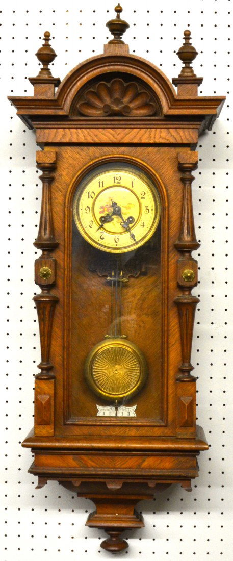 German Cased Pendulum Wall Clock. Spring driven wo: German Cased Pendulum Wall Clock. Spring driven works by: B P with arrow between. Cast metal bracket attached to inside back of case is marked: Nora, Glockengong, and B P. Arch top oak case with three