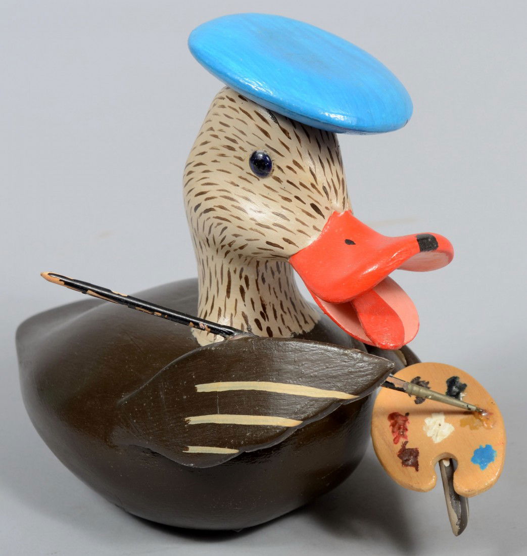 "Coon"Garton signed, "Daffy" Duck. A carved and pa: "Coon"Garton signed, "Daffy" Duck. A carved and painted comical duck model with a blue beret, artists brush and paint palate. Carvers' signature beneath the paint palate with date, '83. 9 1/2"l X 7 3/