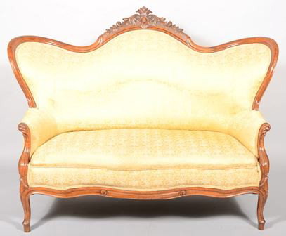 Victorian Carved Walnut Serpentine Back Couch. C: Victorian Carved Walnut Serpentine Back Couch. Carved floral pediment with cartouche. Contoured gold brocaded upholstery also covers arms and back. Carved arm supports and front legs with contoured an