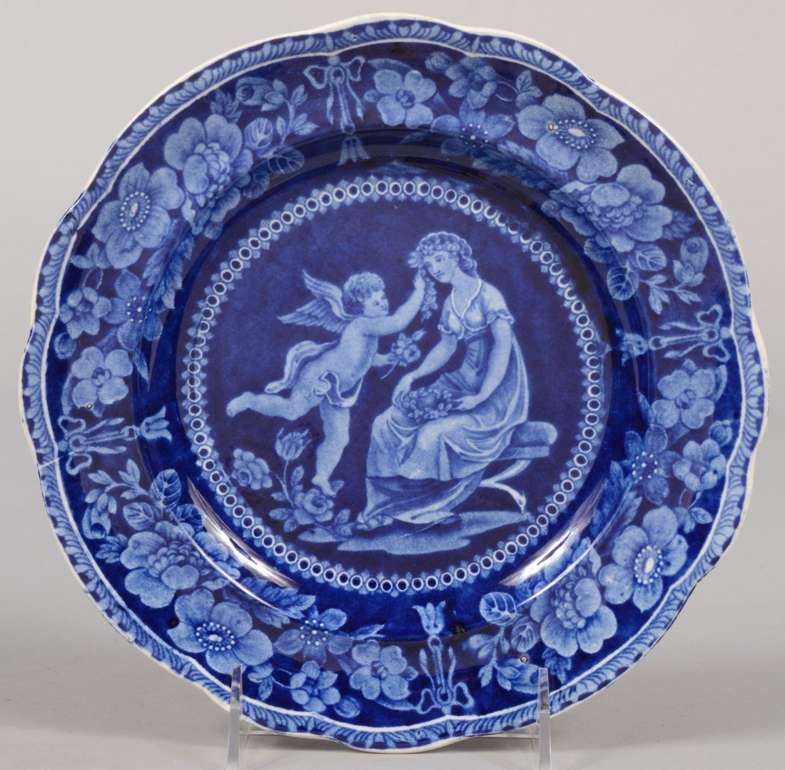 Blue Staffordshire Transfer Plate. Young woman wit: Blue Staffordshire Transfer Plate. Young woman with cupid on center and floral scalloped rim border. Impressed mark on back: "William Adams, Stoke-on-Trent." 9"dia. Condition: Good.