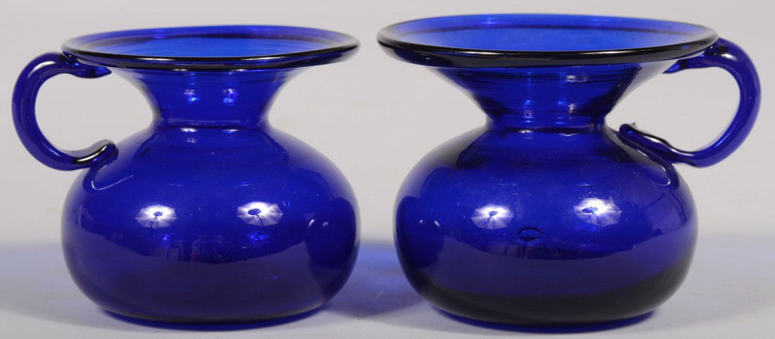 Two Similar Flint Glass Cuspidors. Both cobalt blu: Two Similar Flint Glass Cuspidors. Both cobalt blue flint glass vessels with bulbous base, wide flared mouths with folded rim and applied finger ring. Ground pontil. Unmarked. Both 3 3/8"h. Condition: