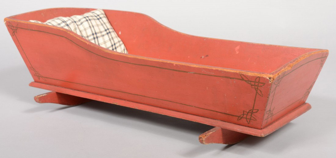 Bright Red Painted Wood Doll Cradle. Low profile d: Bright Red Painted Wood Doll Cradle. Low profile design, mitered corners, gold line decoration. Along with a blue and white tabby pillow. Unmarked. 24"l. X 12"w. Condition: Good with use wear.