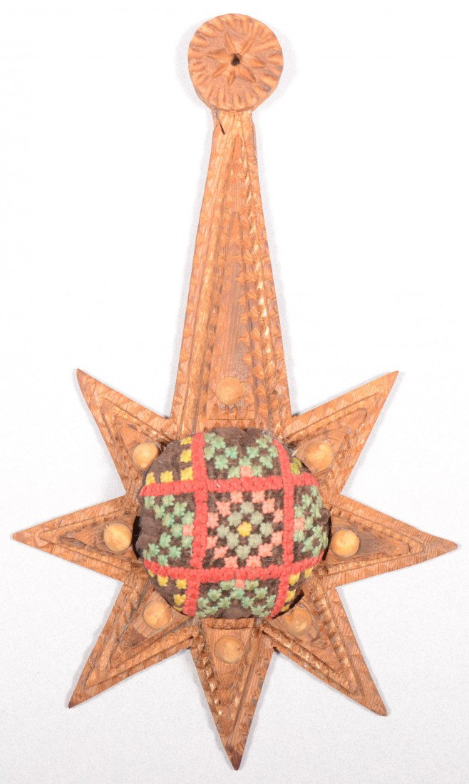 A Pendulous Star Shaped Pin Cushion. Circular need: A Pendulous Star Shaped Pin Cushion. Circular needlepoint cushion suspended in a four layer star shaped chip carved hanger. Top point elongated to circular chip carved finial with perforation. Appears