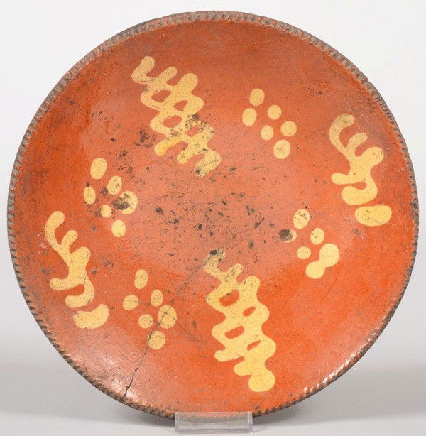 Slip Decorated Redware Plate. Yellow slip in dots a: Slip Decorated Redware Plate. Yellow slip in dots and squiggles. Coggle rim. 10 1/2"dia. Condition: Cross crack on one side from rim. A few small chips off underside of rim.